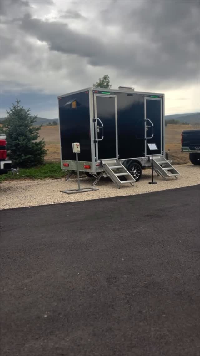 Spotless Stops black double restroom trailer set up outdoors in Utah
